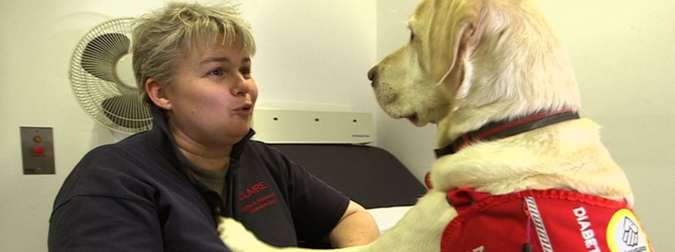 Claire Pesterfield, paciente con diabetes tipo 1, junto a Magic, su perro de detección médica. Imagen: BBC.